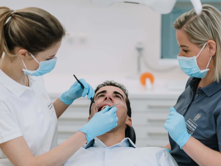 Zahnärtzin und Zahnarztassistenz behandeln einen Patienten